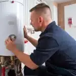Plumber checking a water heater and supply lines during a home inspection