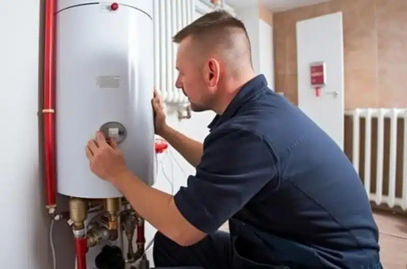 Plumber checking a water heater and supply lines during a home inspection