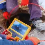 Plumber feeding a sewer inspection camera into a main line cleanout